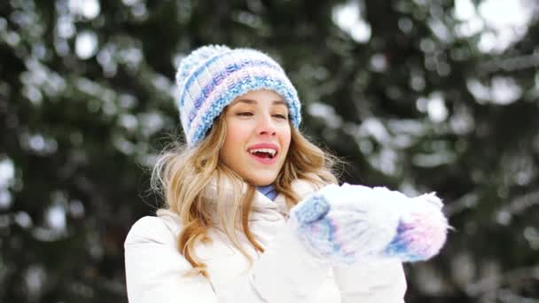 快乐的年轻女子吹雪在冬天的森林
